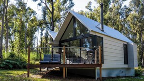 A modern cabin with a balcony, surrounded by trees.
