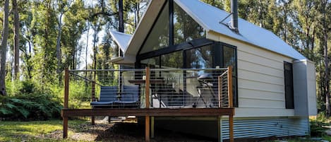 A modern cabin with a balcony, surrounded by trees.