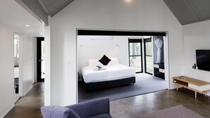 A modern bedroom with a large bed, a desk, and a TV.