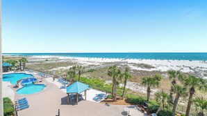 Een resort met een zwembad, toegang tot het strand en palmbomen.