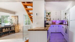 A modern kitchen with white cabinets, a wooden island, and a purple-lit bar area. - L`Oasis Zen bord de L`eau, Spa,Foyer (Nominingue)