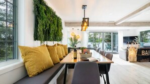 A modern dining area with a long table, bench seating, and a green vertical garden. - L`Oasis Zen bord de L`eau, Spa,Foyer (Nominingue)