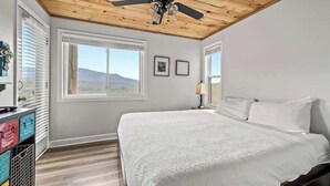 A bedroom with a bed, a ceiling fan, large windows, and a view of the mountains. - Indoor Pool Sleeps 6 Mountain Views Playground (Gatlinburg)