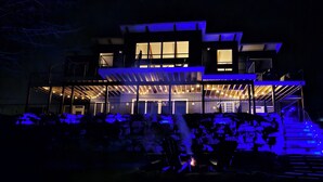 Une maison moderne à deux étages, dotée d’un patio couvert et d’une cheminée.