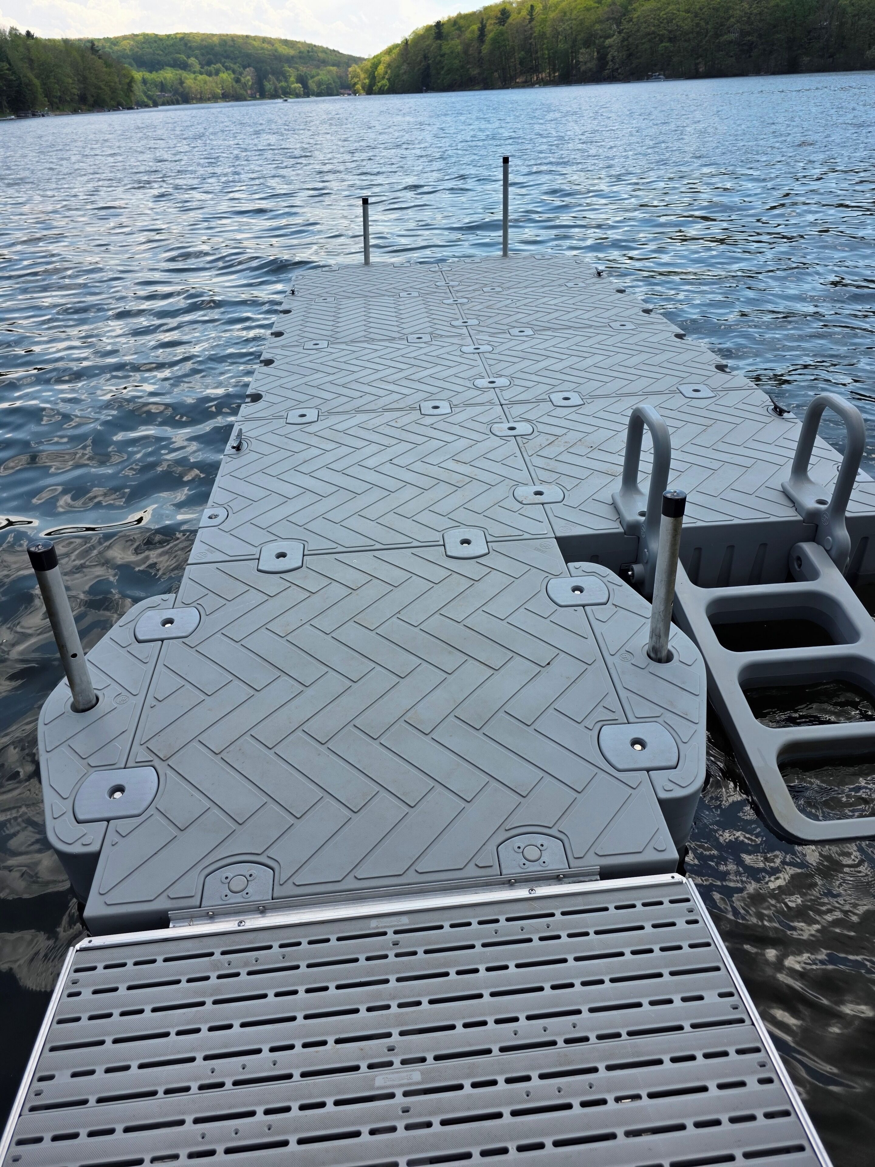 Une jetée s’avançant dans un lac, avec un motif en chevrons et des bornes métalliques.