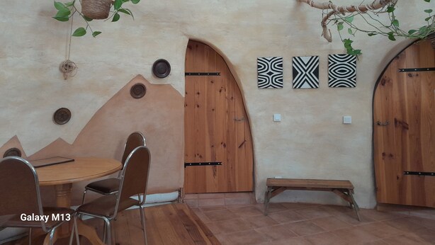 A room with a round table and chairs, wooden doors, and wall-mounted decor.