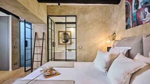 A modern bedroom with a large bed, a ladder, a wooden tray with breakfast, and a bathroom visible through a glass door. - Holiday home with air conditioning and internet (Grožnjan)