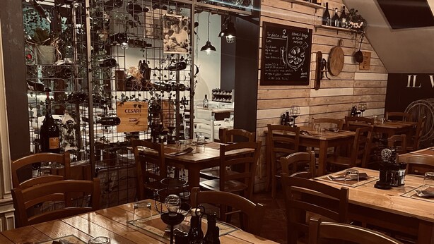A restaurant with wooden tables and chairs, a wine rack, and a chalkboard menu. - Boccadoro Rooms  (Mozzecane)