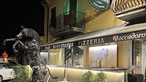 A restaurant named Boccadore with a signboard, a menu stand, and a decorative metal sculpture of a bull. - Boccadoro Rooms  (Mozzecane)