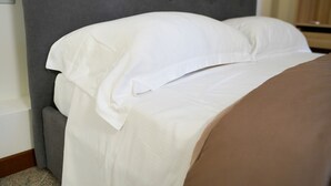 A neatly made bed with white linens and a brown blanket, a grey upholstered headboard, and a wooden nightstand. - Boccadoro Rooms  (Mozzecane)