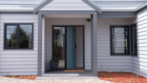 A modern house with a grey exterior, a blue door, and a small porch area with a potted plant. - Moon Pot at Waters Edge (Mount Martha)