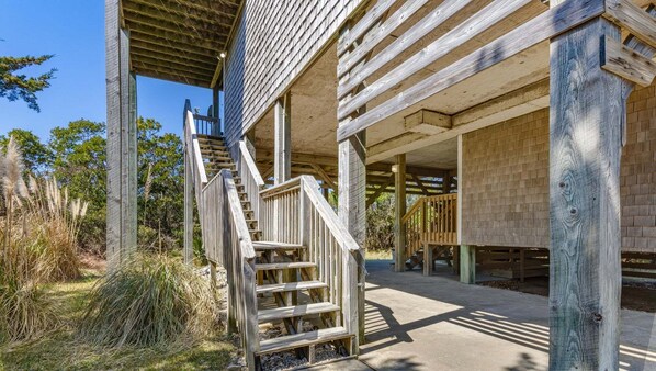 A wooden staircase leading to a covered porch area with a brick wall in the background. - 4 br, 2 Min Walk to Beach, hot tub, water view (Avon)