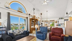 A spacious living room with a large window, a dining area, and a kitchen. - 4 br, 2 Min Walk to Beach, hot tub, water view (Avon)