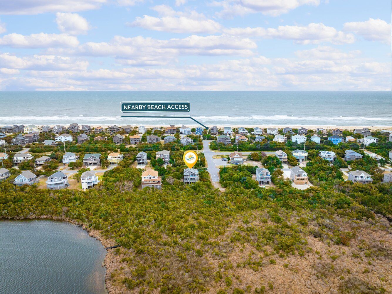 An aerial view of a coastal residential area with houses and a nearby beach access point.