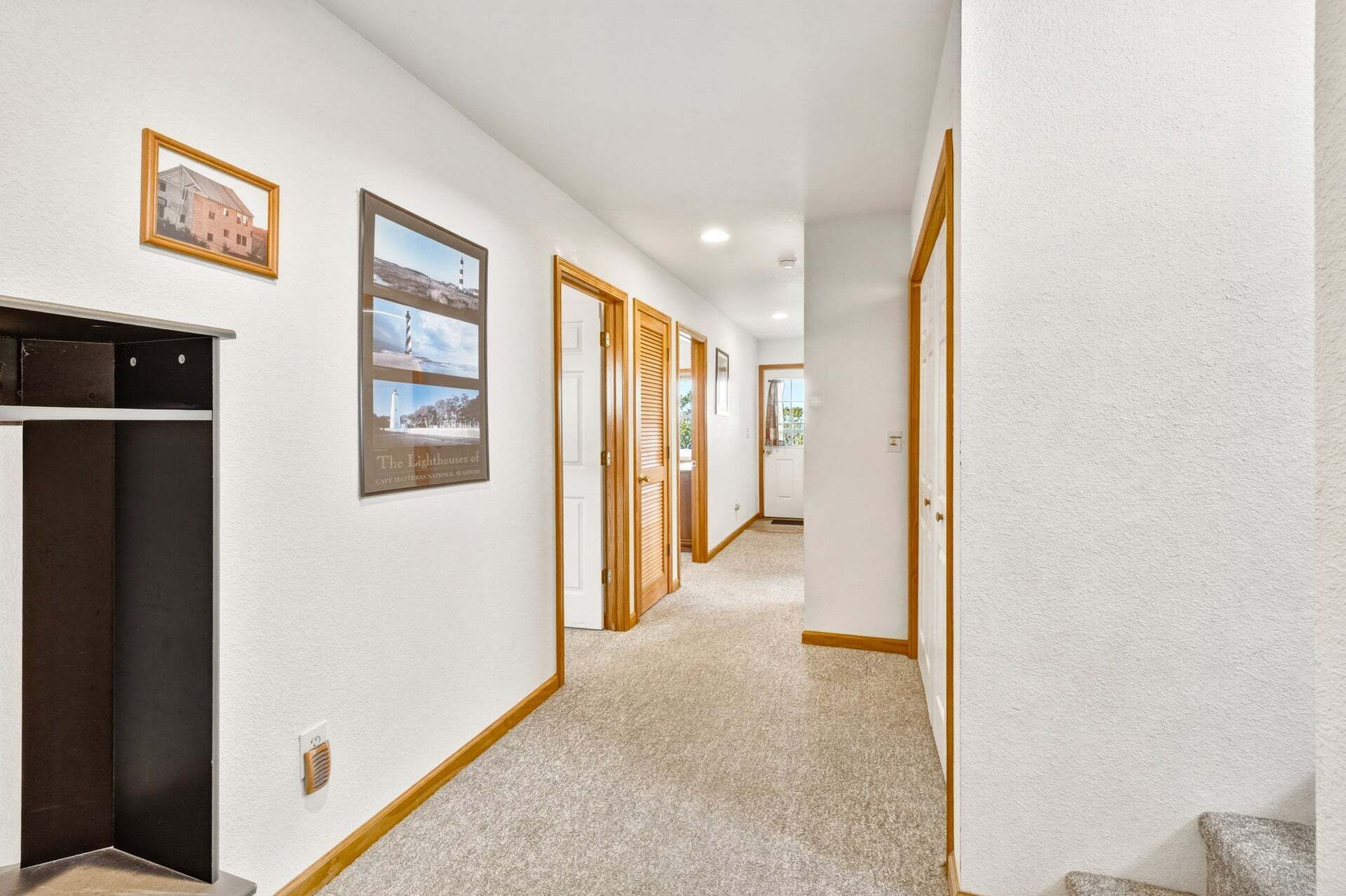 A hallway with a coat rack, framed pictures, and doors leading to rooms.