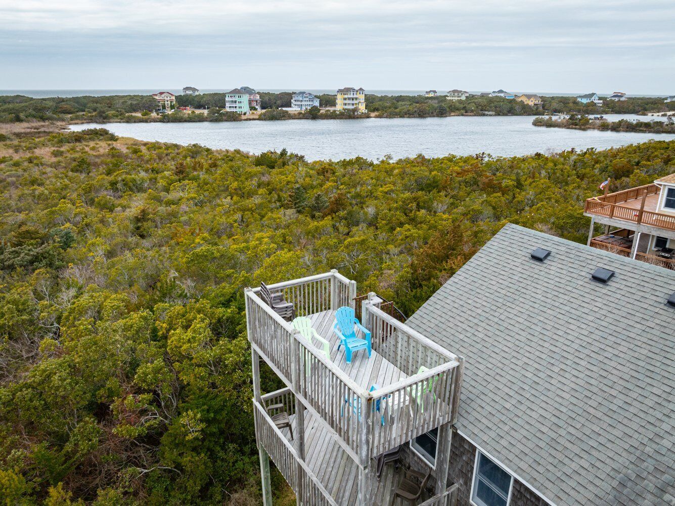 A wooden deck with outdoor seating, overlooking a body of water and a coastal landscape.