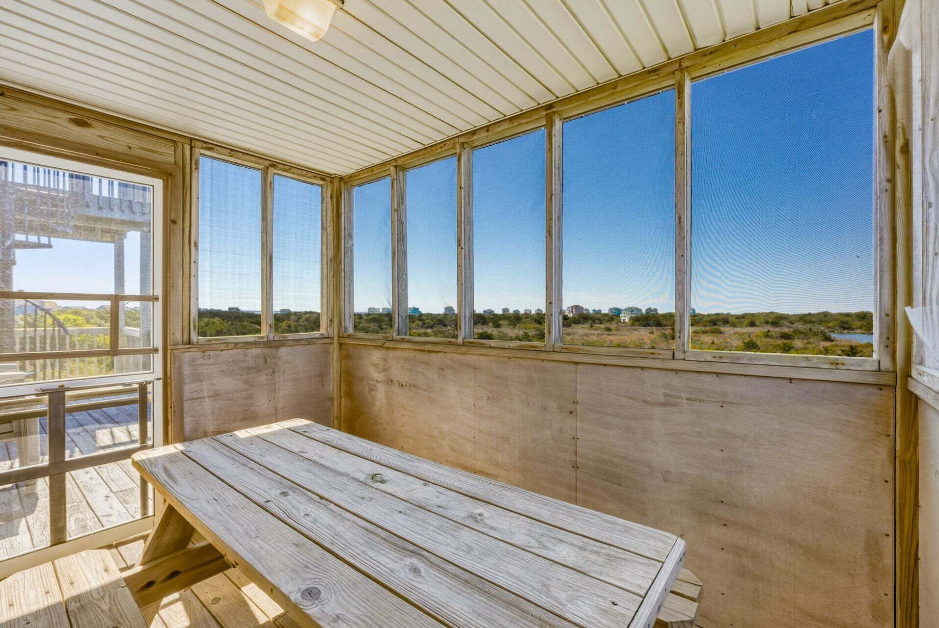 Une pièce avec un banc en bois, de grandes fenêtres et une vue sur un paysage.