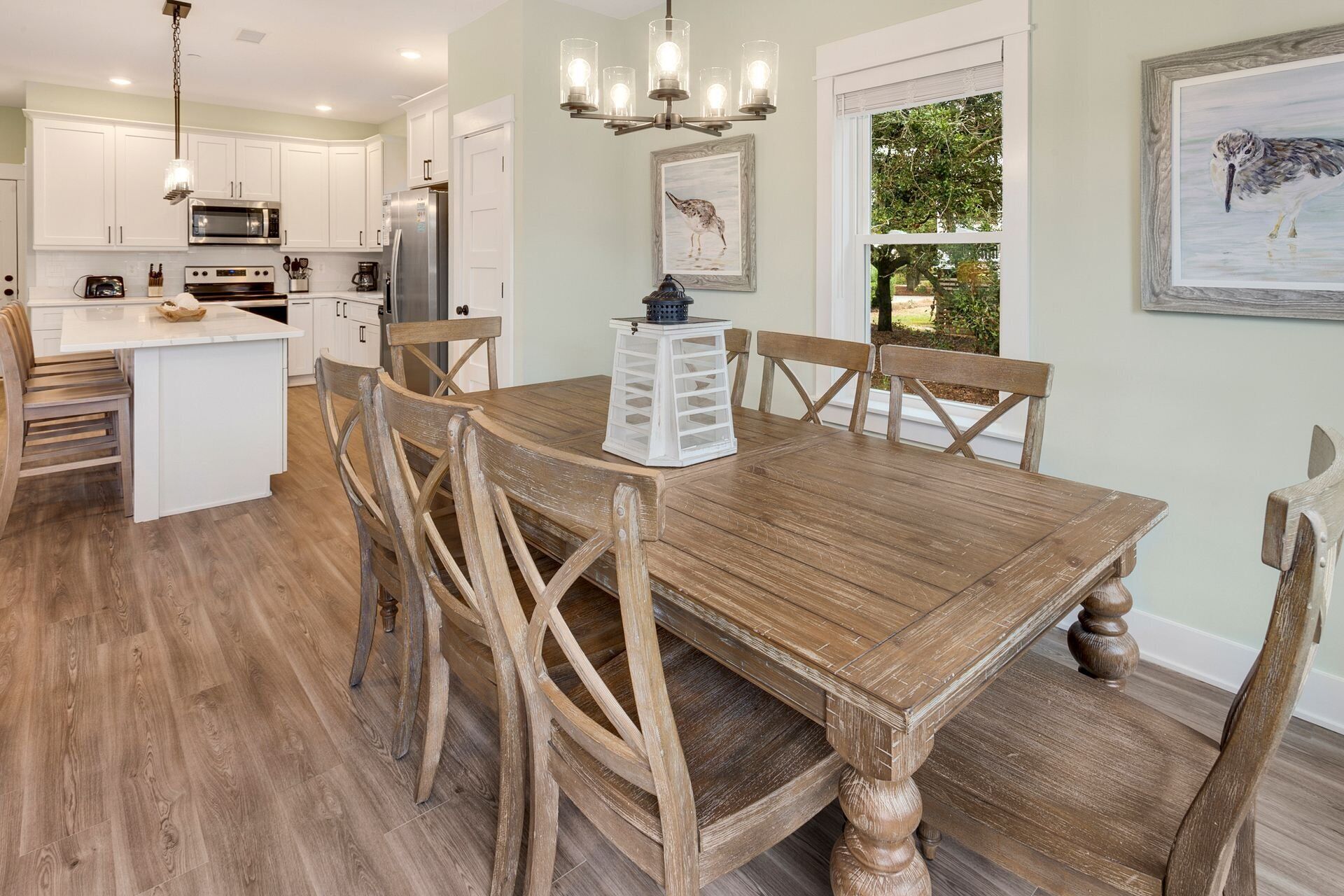 A modern kitchen with white cabinets, stainless steel appliances, and a wooden dining table with six chairs.