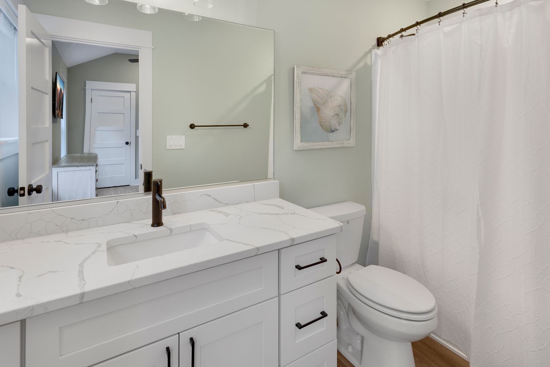 Une salle de bain avec un lavabo en marbre blanc, des toilettes blanches et un rideau de douche.