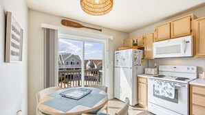 A kitchen with wooden cabinets, a white stove, a microwave, and a refrigerator.