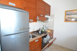 A kitchen with wooden cabinets, a stainless steel refrigerator, a dishwasher, and a stove.