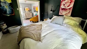 Um quarto com uma cama grande, uma mesa de cabeceira, um abajur e um quadro na parede.