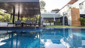 Ein moderner Poolbereich im Freien mit Liegestühlen und einem überdachten Sitzbereich.