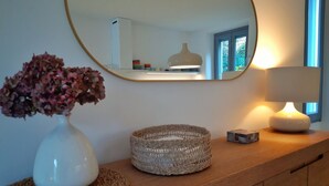 A wooden dresser with a woven basket, a white vase with flowers, and a lamp. - Casa Beverly 2 - My Home in Como (Argegno)