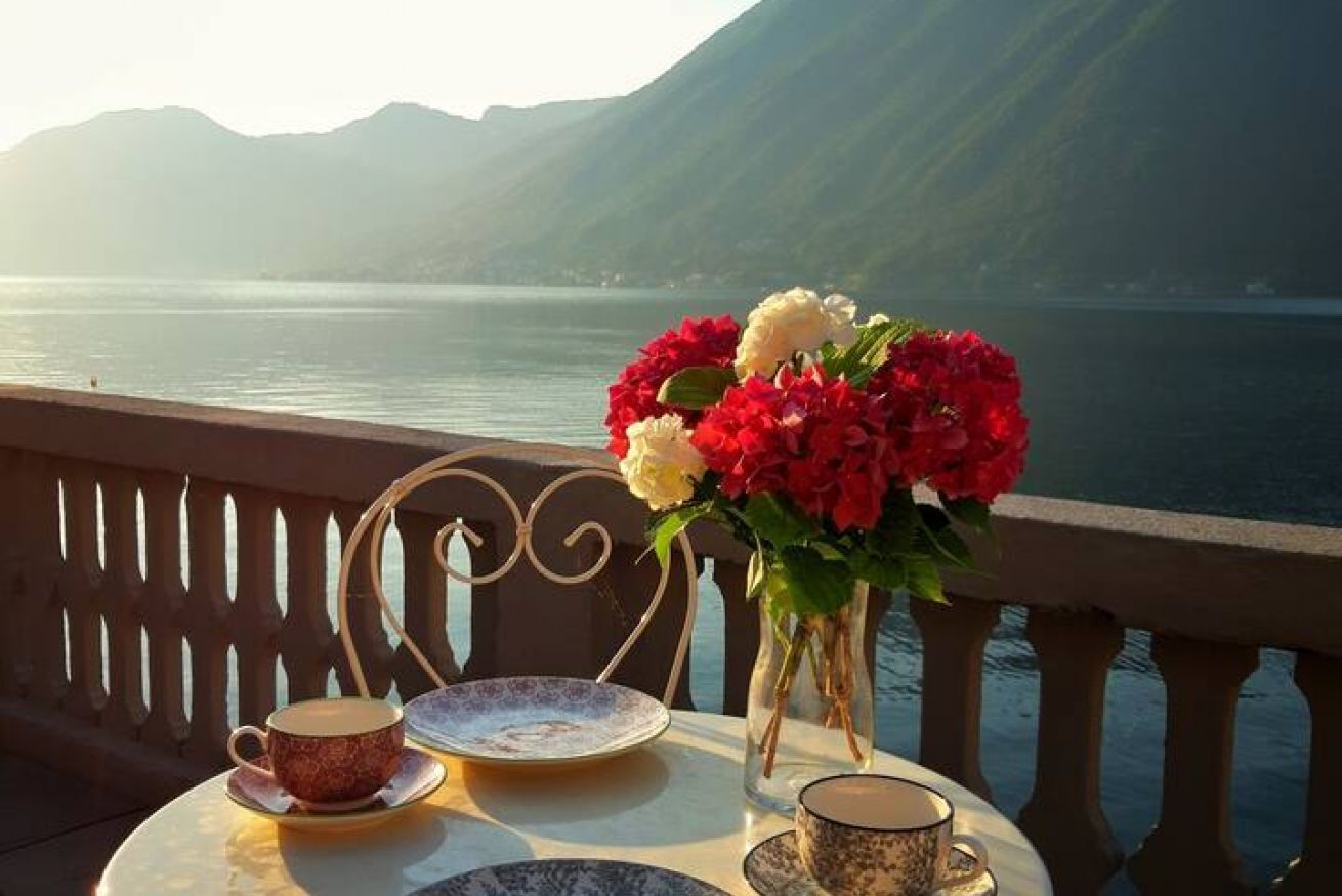 A table with a vase of flowers, a cup, and a saucer.