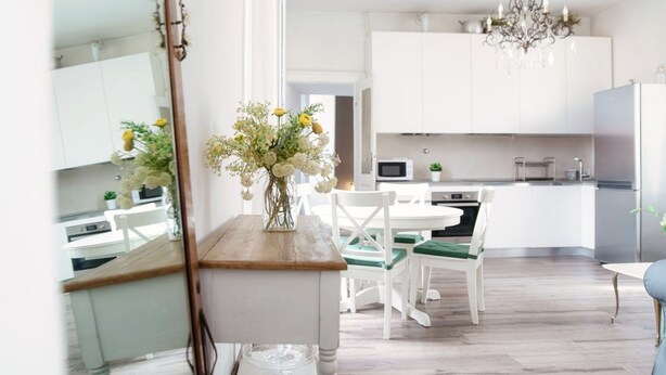 Una cocina moderna con armarios blancos, una mesa de comedor de madera y una araña.