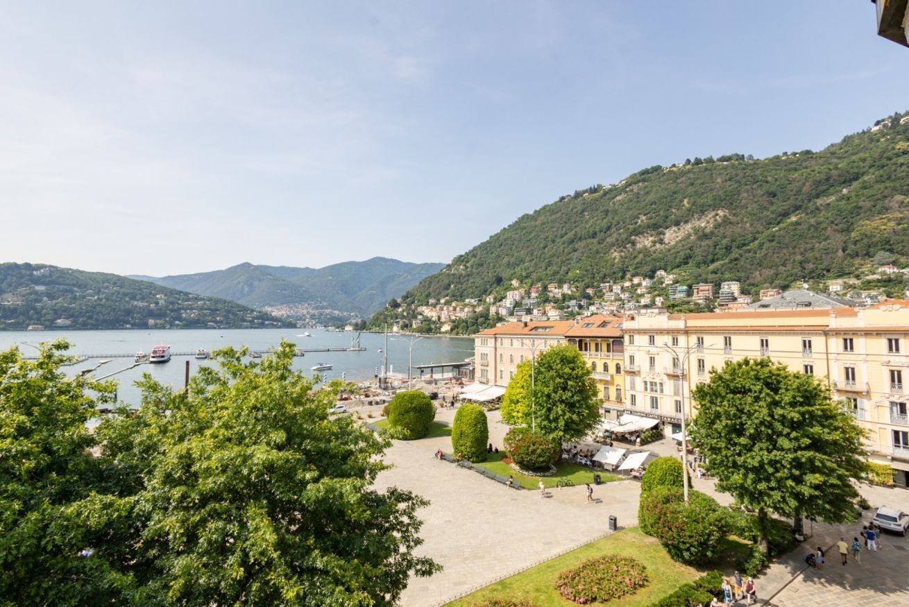 A coastal town with buildings, a marina, and a hill with greenery.