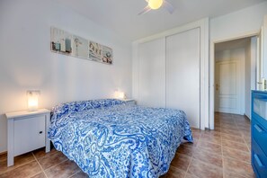 A bedroom with a bed, nightstands, a ceiling fan, and a door leading to another room. - Holiday Apartment "Sauce Sol Fuengirola" with Sea View, Shared Pool & Private Terrace (Fuengirola)