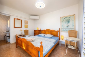A bedroom with a wooden bed, bedside tables, a chair, a desk, and a painting on the wall.