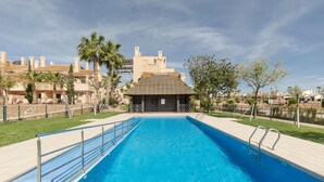 Ein rechteckiger Swimmingpool mit Metallgeländer, umgeben von einer gepflasterten Terrasse.