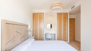 Ein Schlafzimmer mit einem großen Bett, einem Holfischschrank, einem Schreibtisch mit Stuhl und einem runden Spiegel an der Wand.