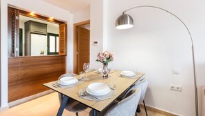 A dining area with a table set for four, a vase with flowers, and a modern pendant light.