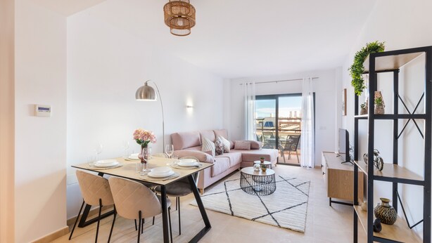 A modern living room with a dining area, a sofa, a coffee table, and a bookshelf.