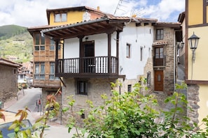 A traditional building with a balcony, stone walls, and a wooden door.
