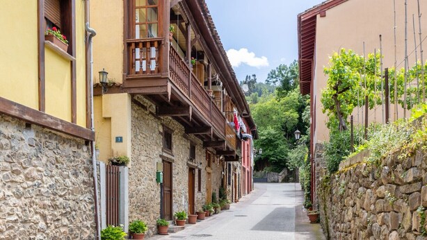 A narrow street with stone buildings, wooden balconies, and potted plants. - Holiday Home 'Casa Raymonde' with Mountain View, Balcony and Wi-Fi (Potes)