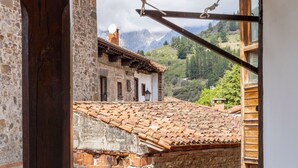 A rustic building with a tiled roof, stone walls, and a view of mountains. - Holiday Home 'Casa Raymonde' with Mountain View, Balcony and Wi-Fi (Potes)