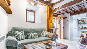 A cozy living room with a green sofa, wooden coffee table, and a window with a curtain. - Holiday Home 'Casa Raymonde' with Mountain View, Balcony and Wi-Fi (Potes)