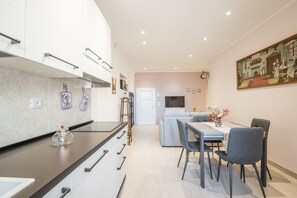 A modern kitchen with a dining area, a sofa, and a painting on the wall. - 'In the Heart of Radicondoli' Apartment with Wi-Fi (Radicondoli)