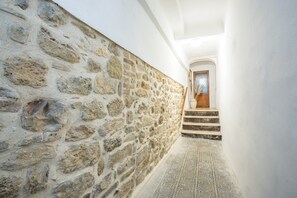 Un muro in pietra, un pavimento decorato e una scala che conduce a una porta.