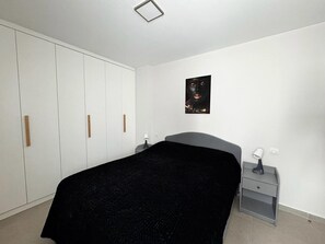 Une chambre à coucher comprenant un lit, une armoire, une table de chevet et un tableau accroché au mur.