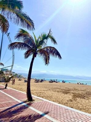 A beach with palm trees, a clear sky, and a distant mountain range. - Holiday Apartment 'Las Palmas Duplex Am Las Canteras' with Sea View and Wi-Fi (Las Palmas de Gran Canaria)