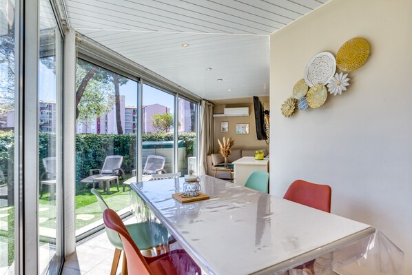 A modern dining area with a large table, chairs, and a view of the outdoor garden.
