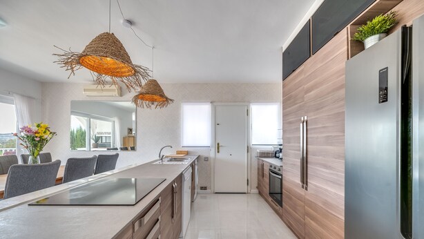 Una cocina moderna con una isla central, armarios de madera y un refrigerador de acero inoxidable.