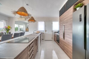 Una cocina moderna con una isla central, armarios de madera y un refrigerador de acero inoxidable.