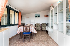 A dining area with a table set for four, chairs, a refrigerator, and a cabinet with glass doors.