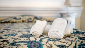 A bed with rolled white towels and a patterned bedspread.